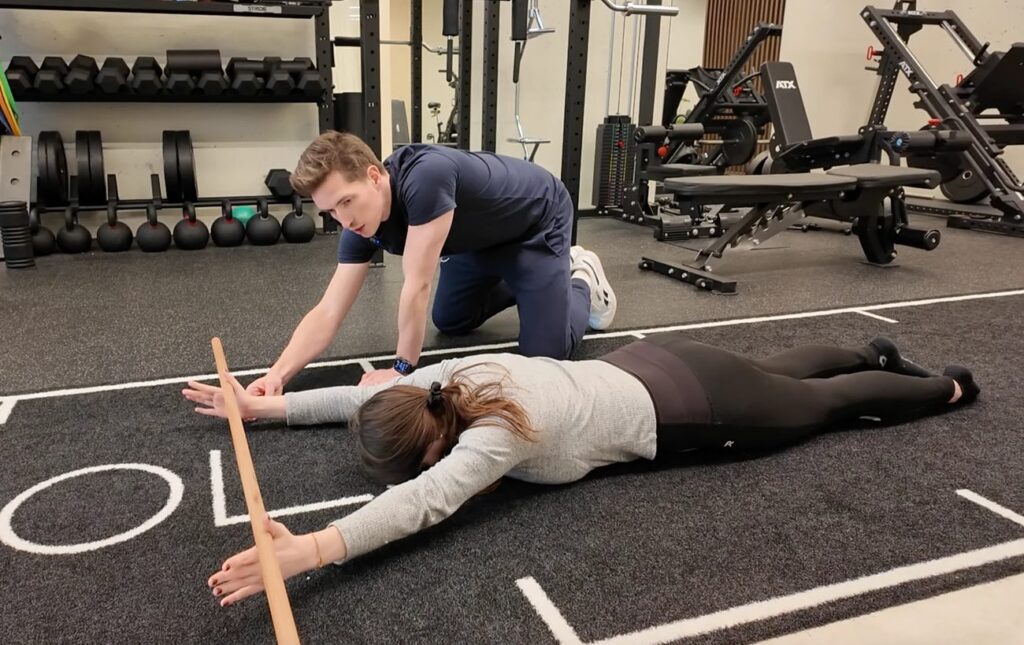 Een Bolster-coach begeleidt een cliënte bij een bewegingsscreening op de trainingsvloer
